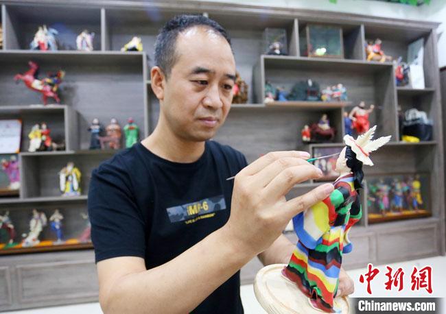 圖為安秋平正在創(chuàng)作代表隴南文縣民俗的《白馬人》作品。　高展 攝