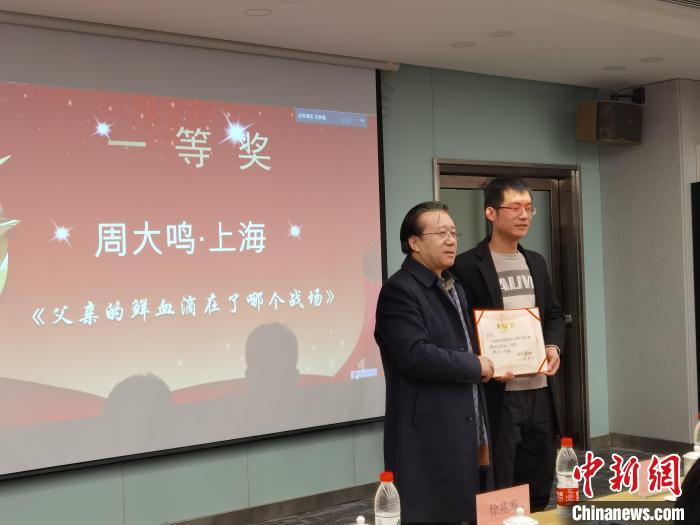 圖為作家、西北師范大學(xué)新聞與傳媒學(xué)院院長(zhǎng)徐兆壽頒發(fā)一等獎(jiǎng)證書，代領(lǐng)獎(jiǎng)?wù)呱吓_(tái)領(lǐng)獎(jiǎng)?！钅?攝