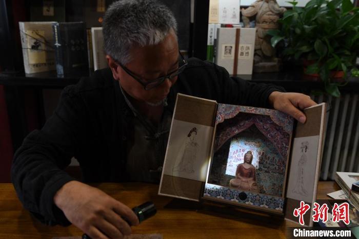 圖為讀者出版集團(tuán)讀者晉林工作室獨(dú)立出品人徐晉林，展示互動(dòng)性強(qiáng)的敦煌題材手工書。(資料圖) 楊艷敏 攝