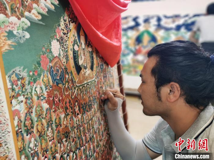 圖為更登才讓的徒弟繪畫唐卡?！?zhí)砀?攝