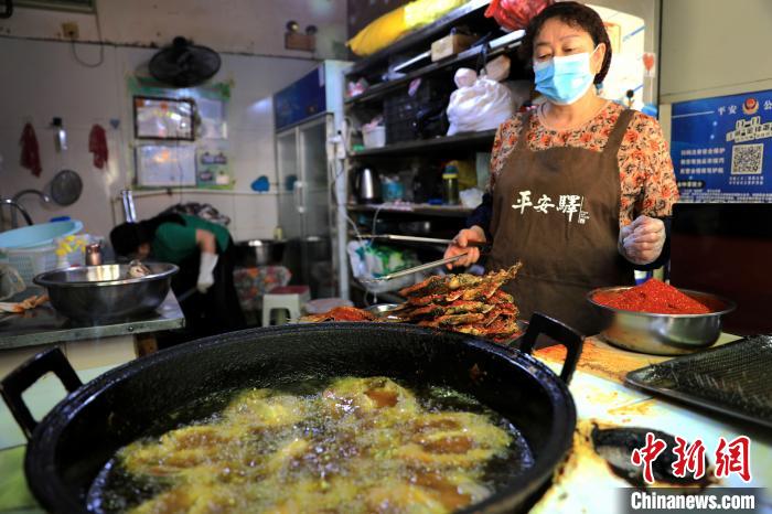 圖為平安驛·河湟民俗文化體驗(yàn)地內(nèi)的商戶炸干板魚?！⊙Φ?攝
