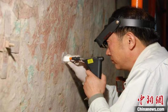 敦煌研究院研究員樊再軒進行壁畫修復。(資料圖)張云文 攝